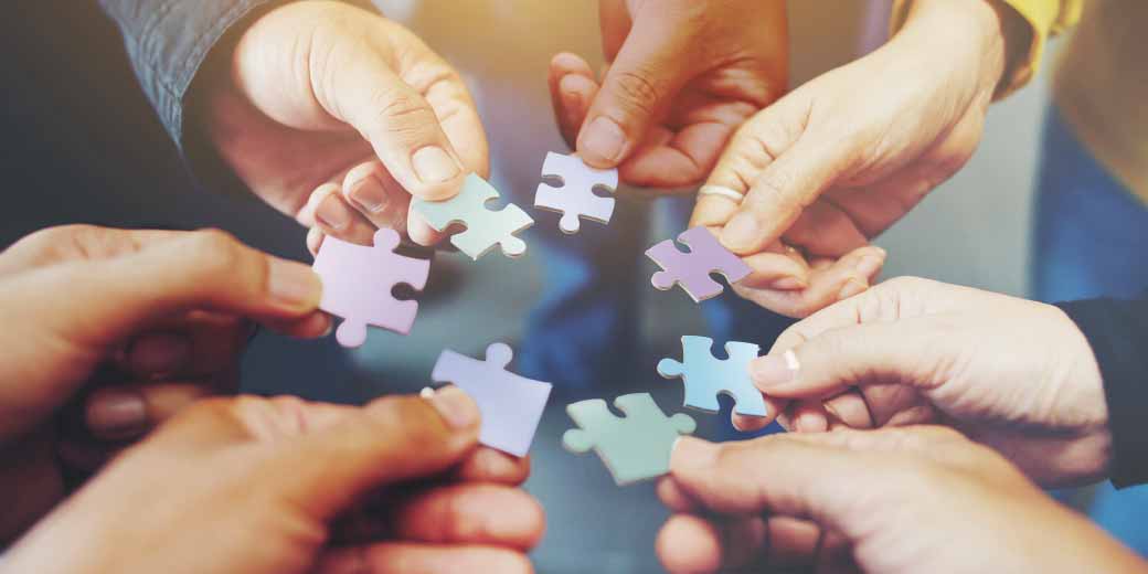 photo of diverse hands putting a puzzle piece together