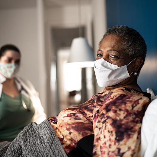 Photo of senior woman in bed, wearing a face mask