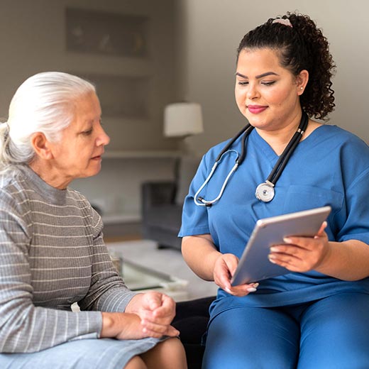 Photo of healthcare professional going over tablet with a patient, with the Your CarePlan icon on the right